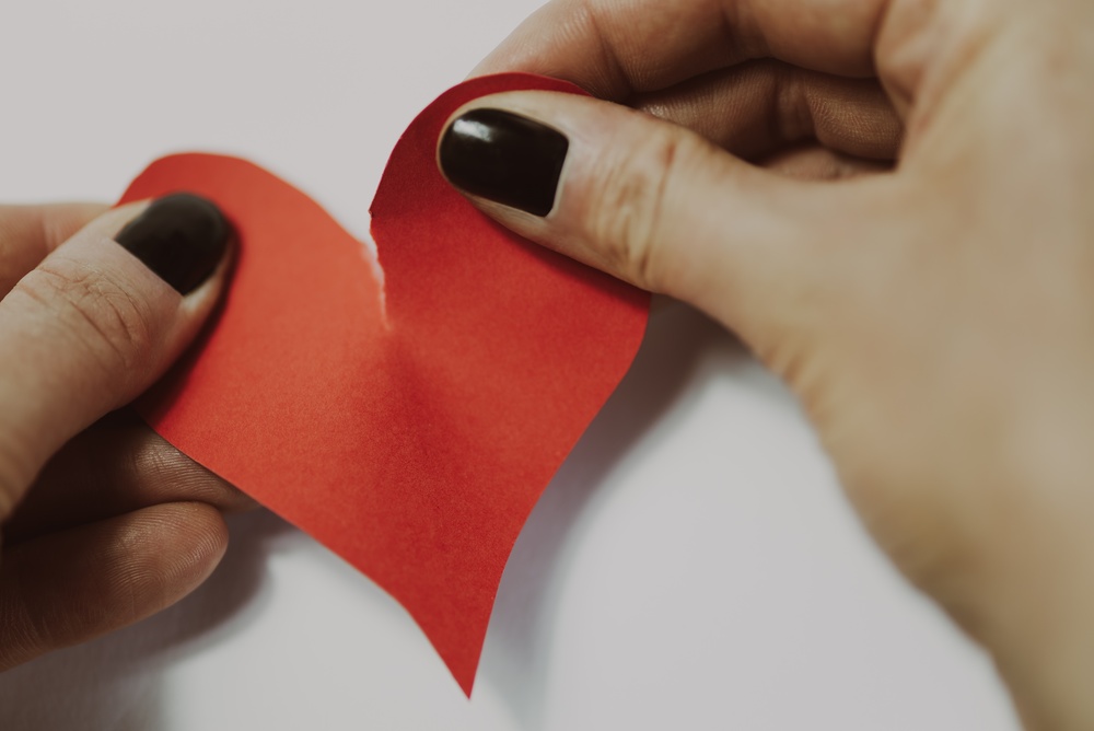 Des mains déchirent un coeur en papier